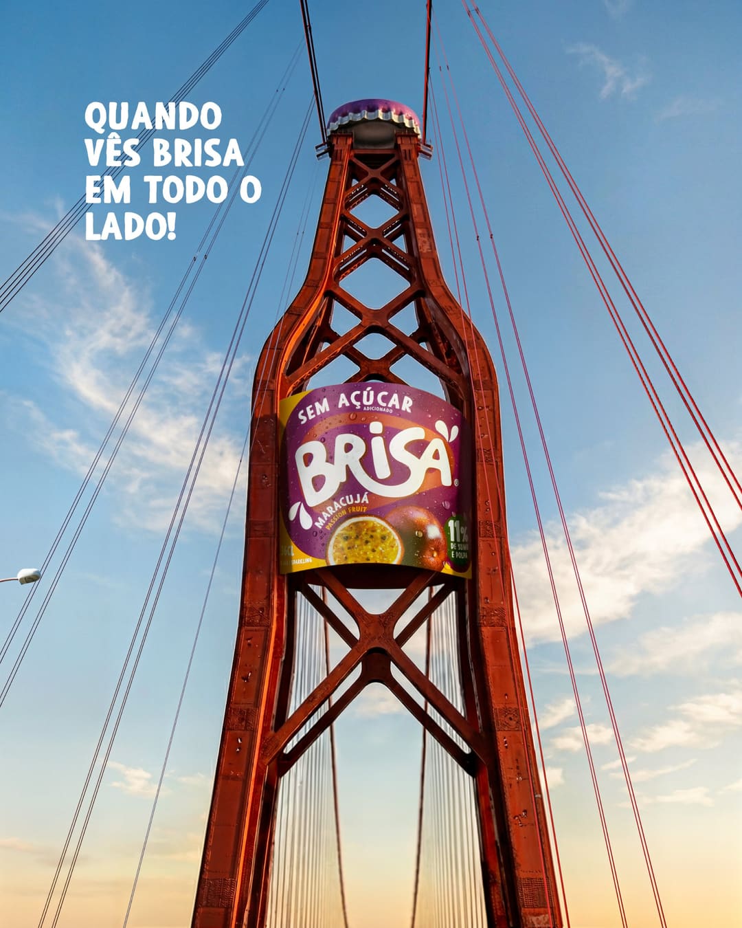 The red tower of a suspension bridge, seen from below against the blue sky, its top shaped like a bottle, with a purple cap and the Brisa Maracujá label. On the left, “Quando vês Brisa em todo o lado!”.