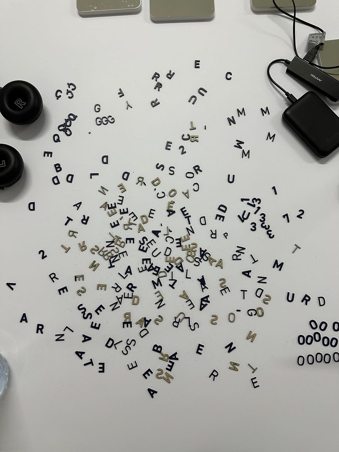 Letras e números em relevo, azuis e creme, espalhados sobre a mesa branca.