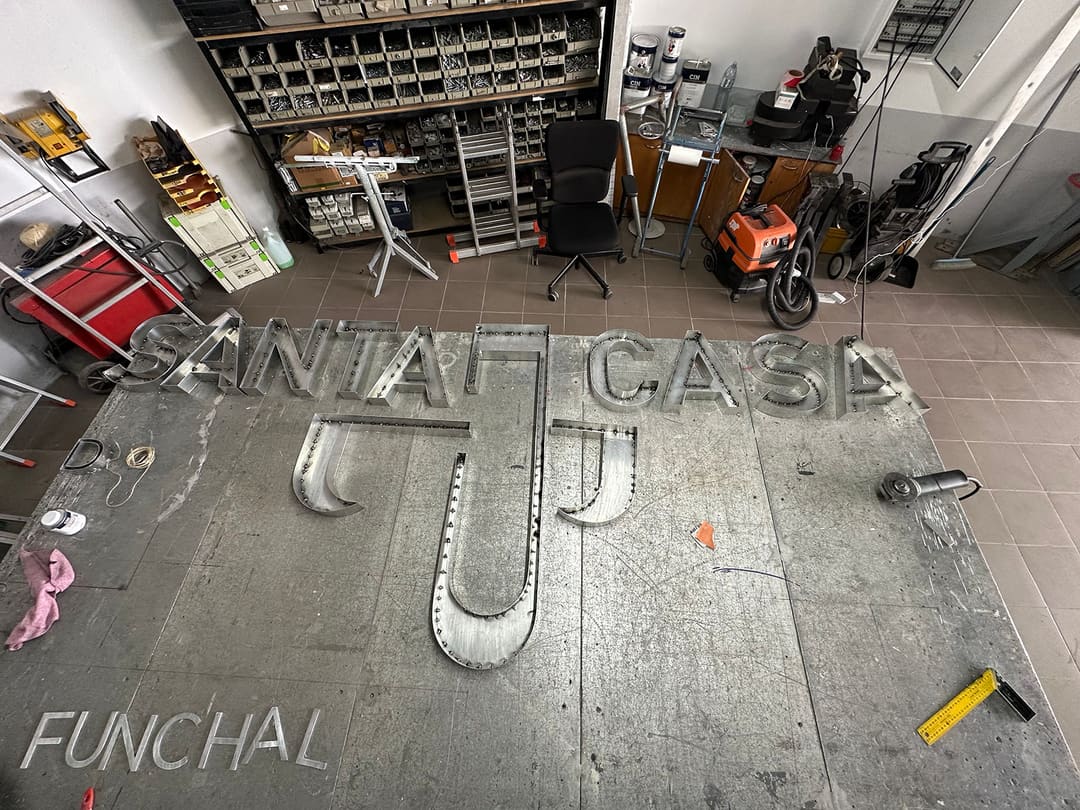 O símbolo e «Santa Casa» em letras de metal, na bancada.