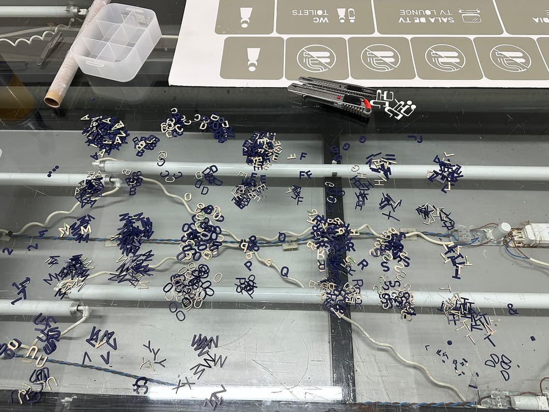 Letras em relevo azuis e creme separadas por montes, ao lado da folha de pictogramas.