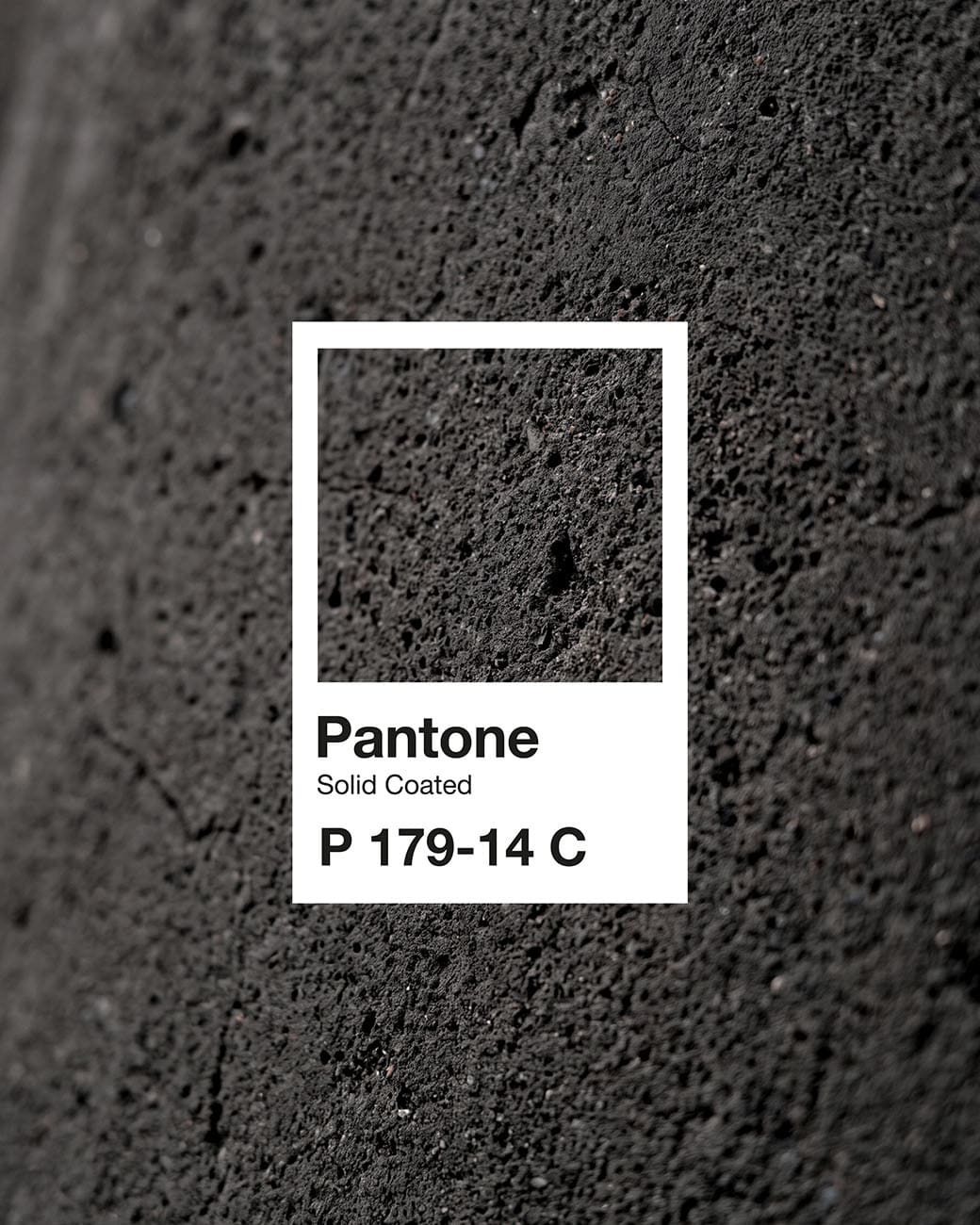 Uma amostra Pantone P 179-14 C sobre uma superfície de pedra escura e porosa.