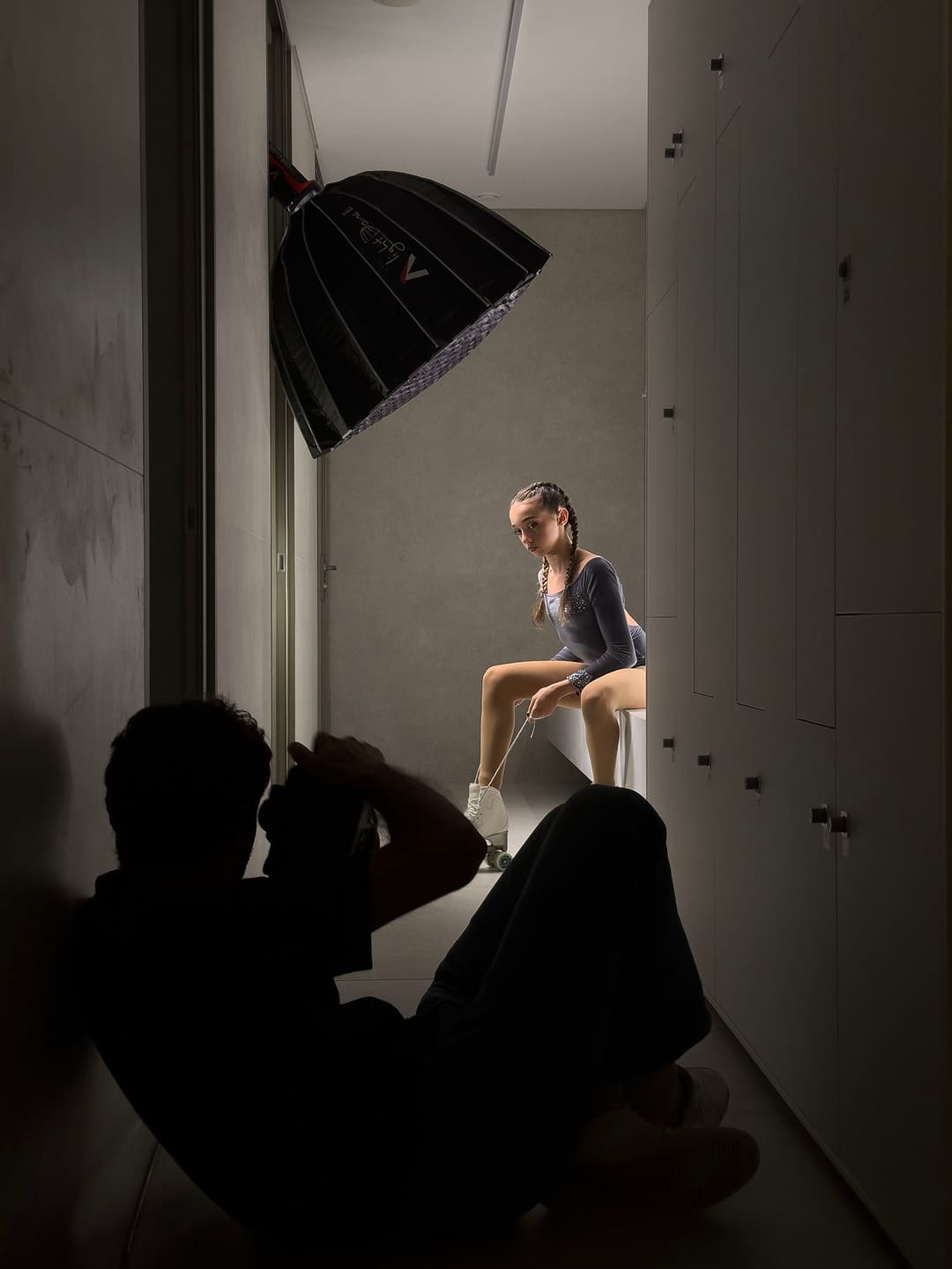 Madalena Costa sentada a apertar os patins, sob uma softbox, com o fotógrafo em silhueta em primeiro plano.